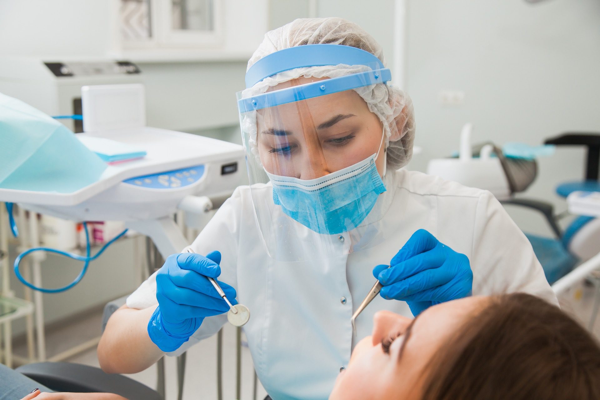 Dentist with mask treats young patient who's experiencing dental pain